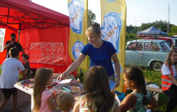 Katarzyna Szczygieł i zainteresowani czytelnicy przy stoisku bibliotecznym