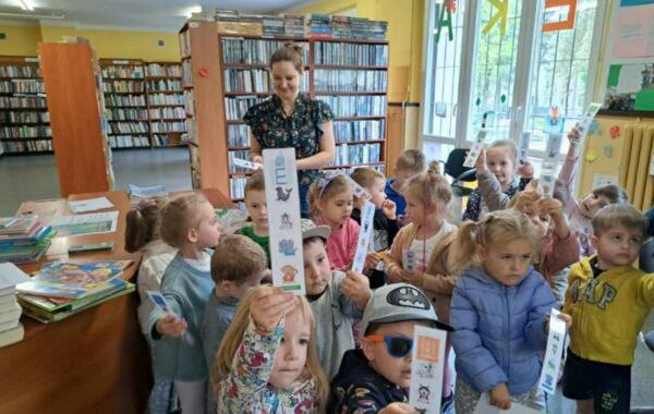 Bibliotekarka oraz przedszkolaki trymające w rączkach zakładki do książek