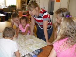 Katarzyna Szczygieł pokazuje dzieciom mapę Polski podczas lekcji bibliotecznej