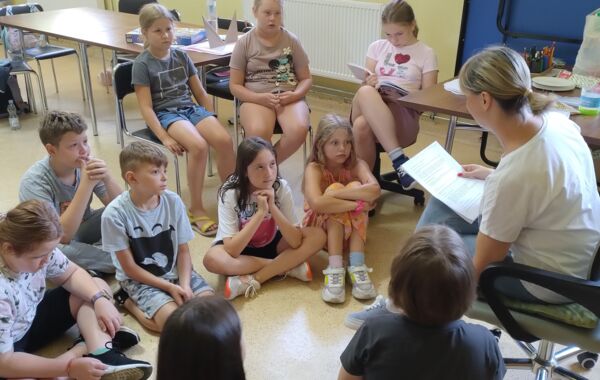 Dzieci podczas słuchania czytającej bibliotekarki