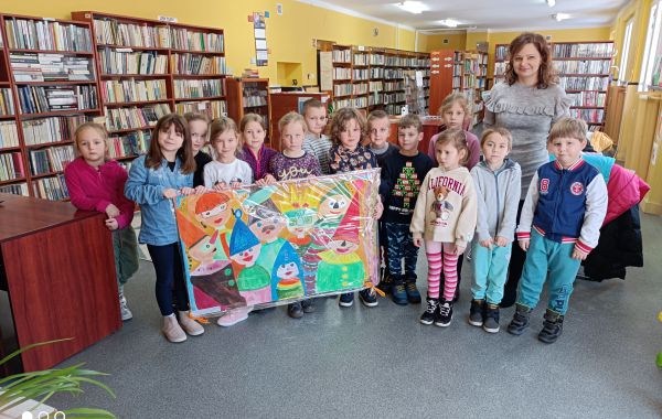 Przedszkolaki wraz z bibliotekarzem i obrazem – niespodzianką namalowanym przez dzieci