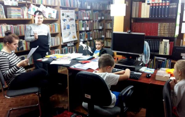 Pracownik filii czyta wraz z dziećmi wiersze Jana Brzechwy oraz Juliana Tuwima