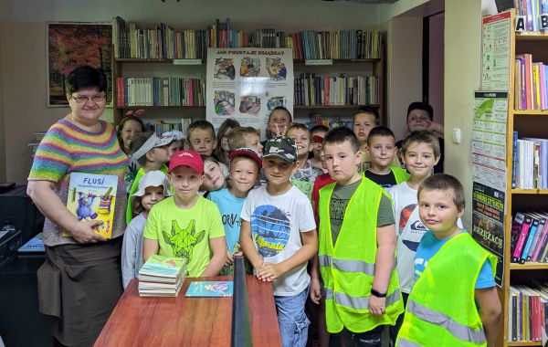 Bibliotekarz wraz z uczniami podczas lekcji bibliotecznej w Bolęcinie. W tle – regały z książkami