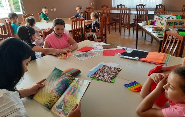Dzieci słuchają czytanej przez bibliotekarza bajki o Czerwonym Kapturku