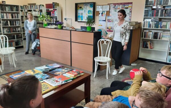 Bibliotekarz oraz dzieci biorące udział w lekcji bibliotecznej