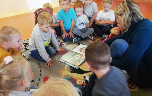 Bibliotekarz otoczony dziećmi w trakcie głośnego czytania