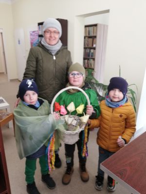 Troje dzieci wraz z wychowawczynią i koszem z papierowymi kwiatami