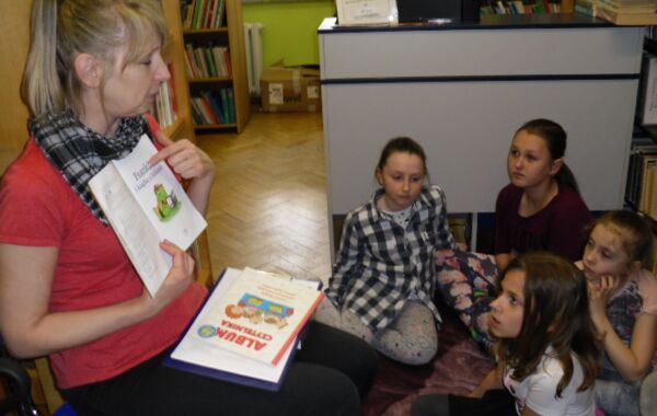 K. Szczygieł prezentuje książkę dzieciom w trakcie lekcji bibliotecznej