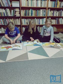 Dzieci podczas czytania książek na dywanie w kąciku do zabaw