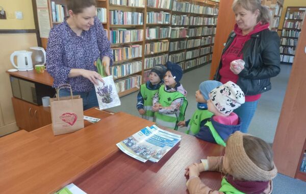 Przedszkolaki z wychowawczynią przy biurku bibliotecznym