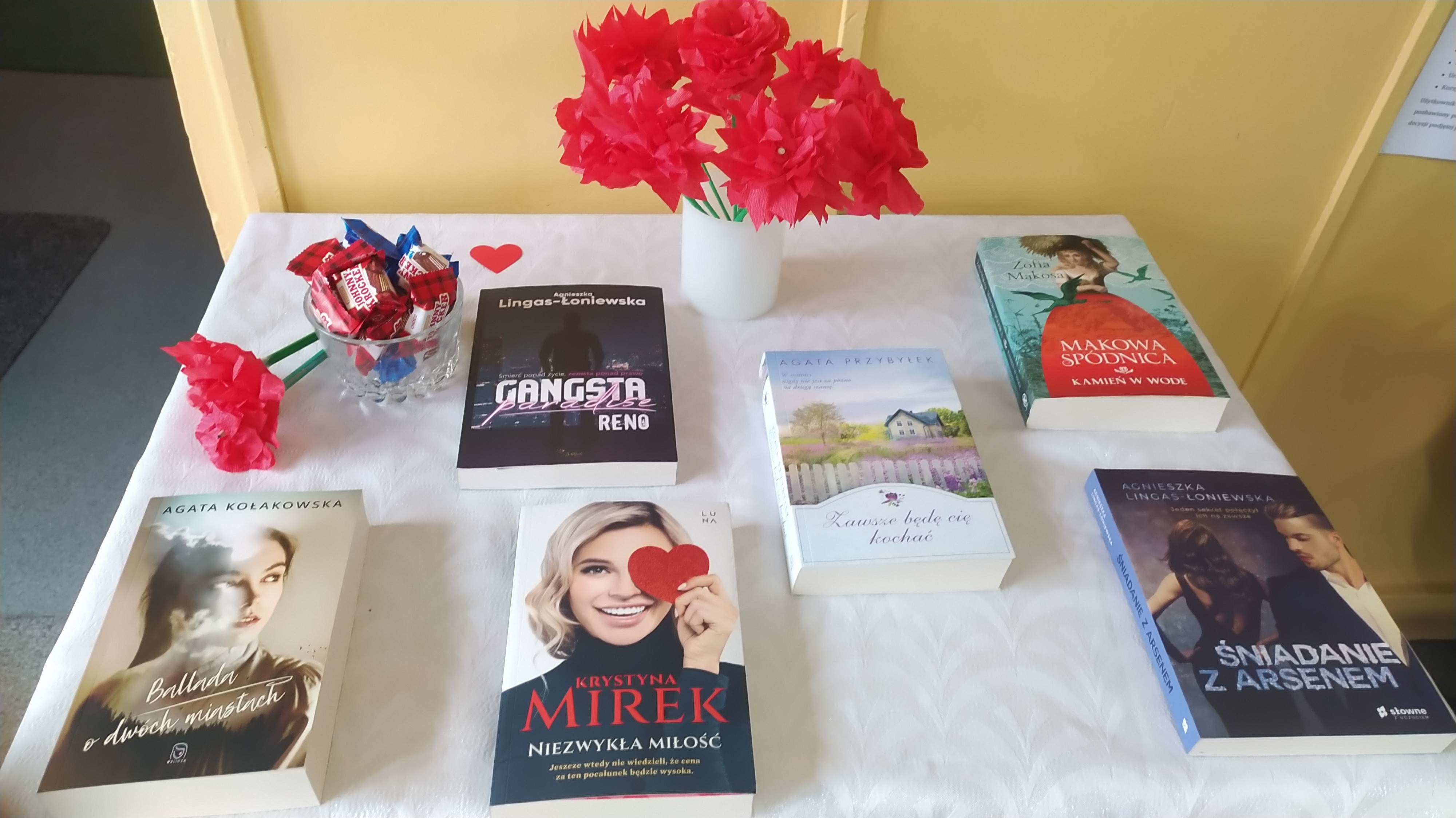 Stolik przygotowany z myślą o Dniu Kobiet, a na nim kwiaty z bibuły i książki polskich autorek